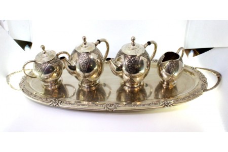 Serviço de chá e café composto por chaleira, cafeteira, açucareiro e leiteira com bandeja em prata com relevos e recortes.